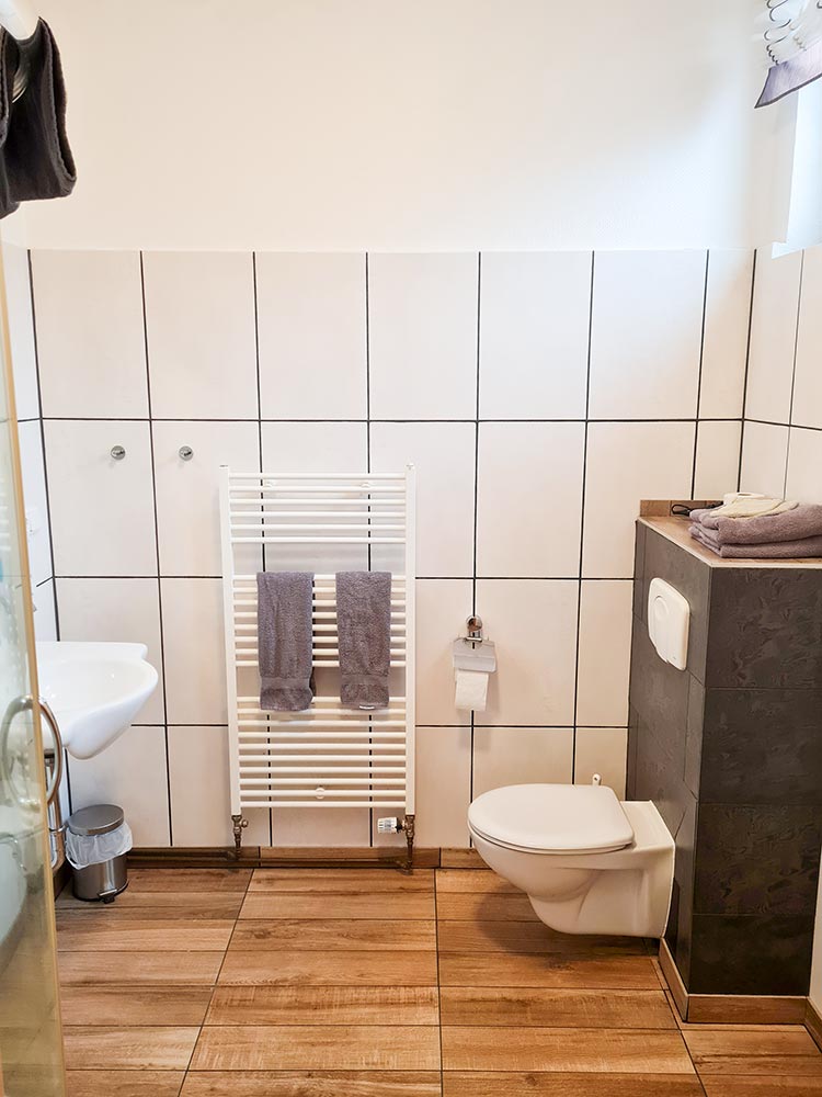 Ein modernes Badezimmer mit weißer Fliesenwand und Holzboden.