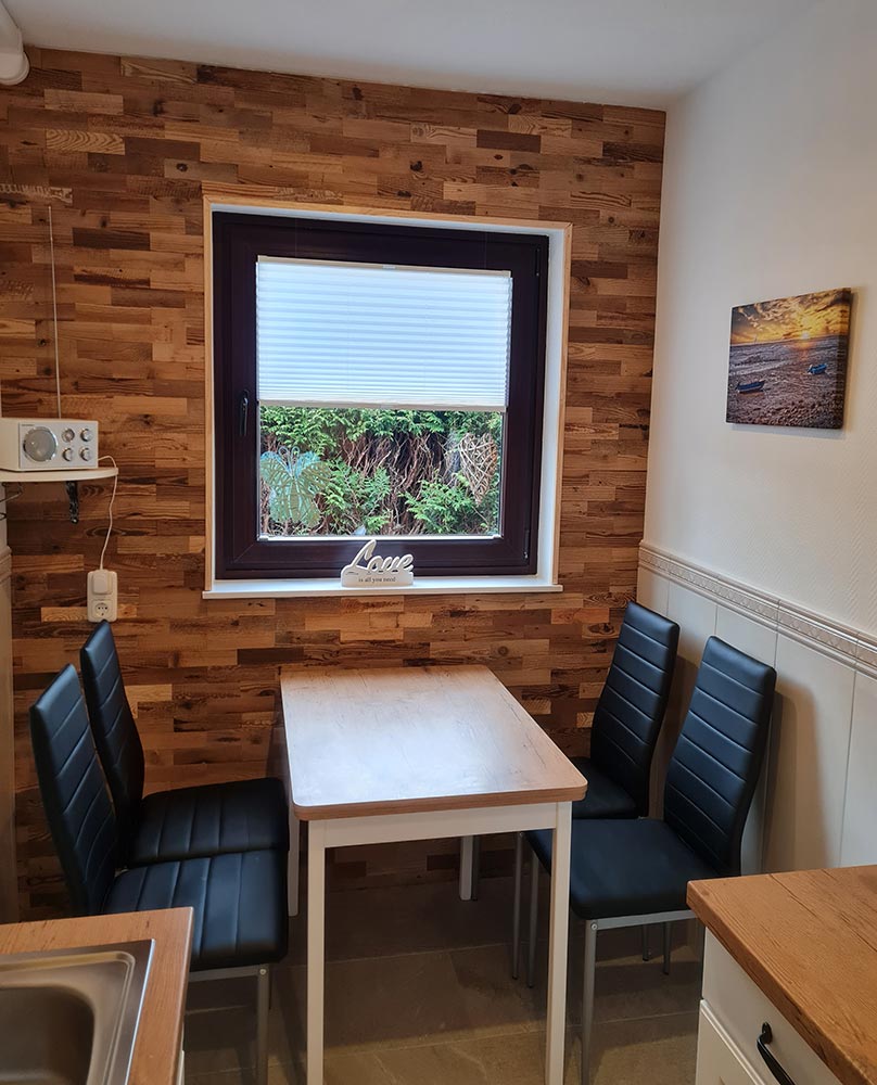 Kleine Küche mit Holzwand, Tisch und schwarzen Stühlen, Fenster mit Jalousie, Dekoration "Love".
