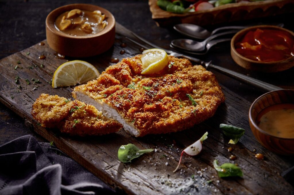 Delicious schnitzel with fresh lemon slices and assorted sauces