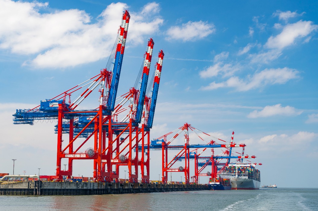 Gantry cranes unload a container ship on the Jade Weser in Wilhelmshaven, Lower Saxony - photo taken from the seaside